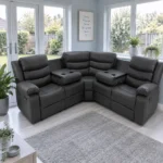 Black corner leather recliner sofa in a spacious entrance hallway with light blue walls, white trim, wooden flooring, a console table, and large mirror, illuminated by natural daylight.